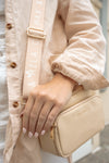 woman wears vegan leather crossbody dog bag in beige.